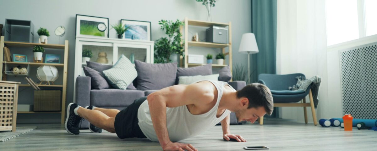 A muscular man performing push-ups in a modern living room, showcasing home fitness.
