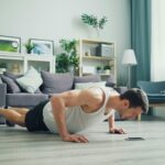 A muscular man performing push-ups in a modern living room, showcasing home fitness.