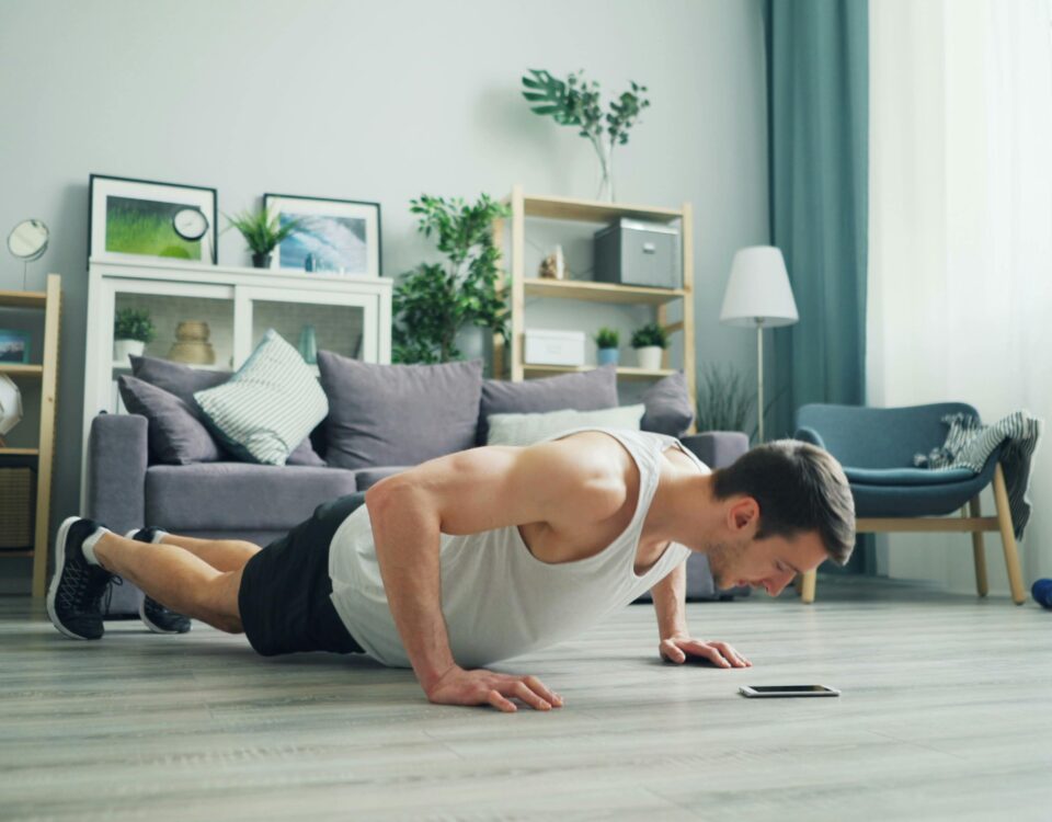 A muscular man performing push-ups in a modern living room, showcasing home fitness.